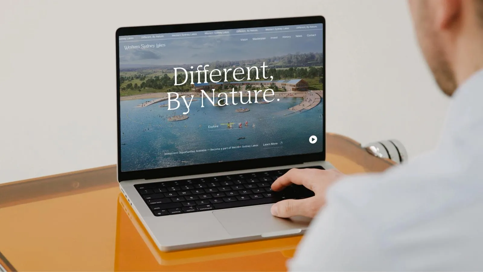 Western Sydney Lakes homepage, "Different, by nature.", open on a laptop over an aerial view of the lakes