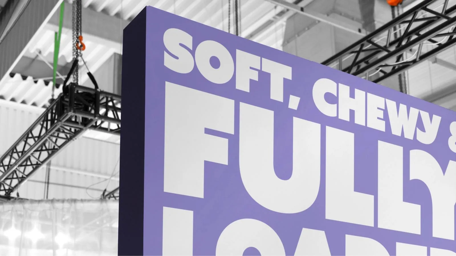 Oversized purple Cookieman sign at an event venue with the line "Soft, chewy & fully loaded"