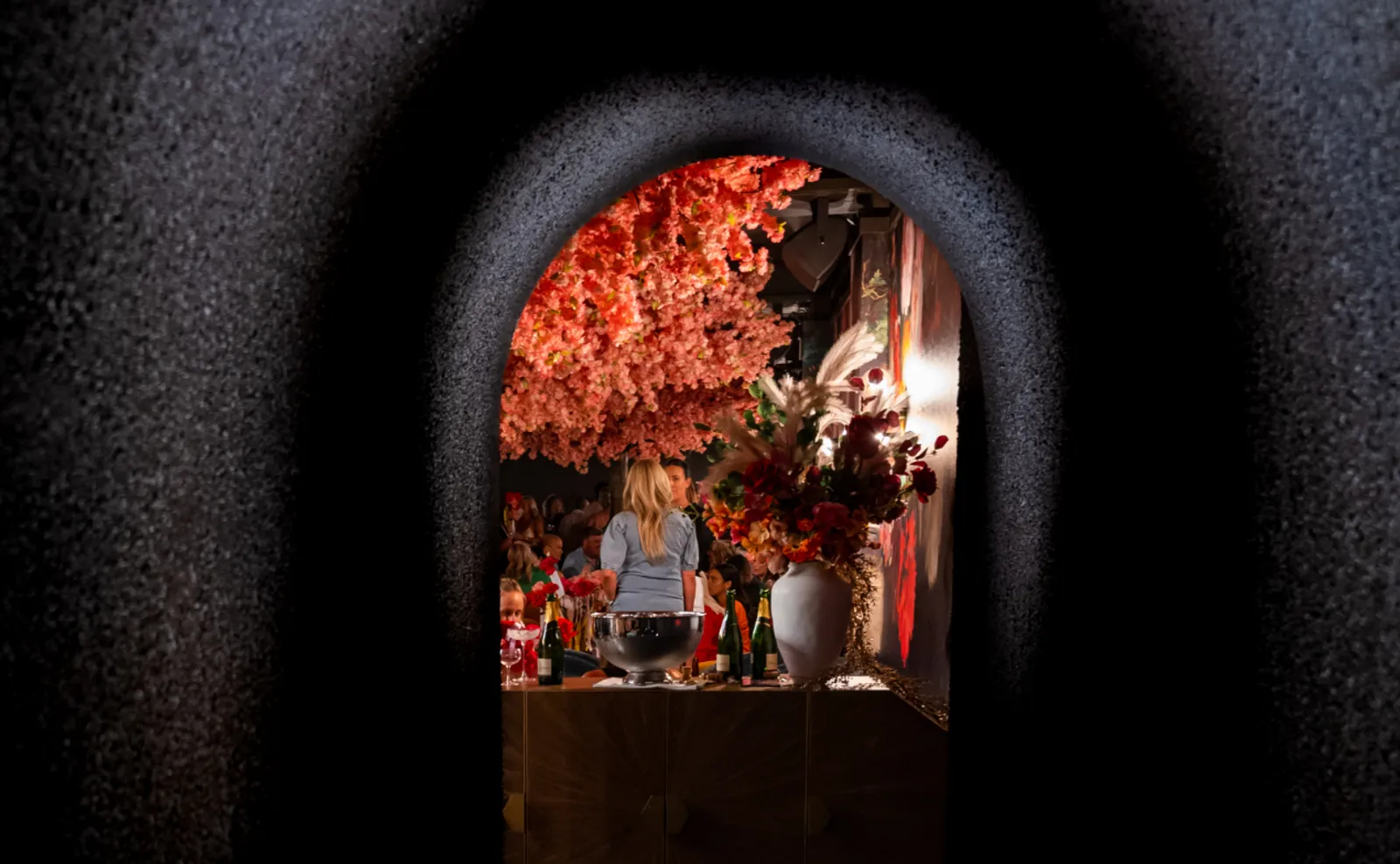 Arched doorway opening into The Flower Shop, Penrith's hidden bar, with a ceiling of blossom inside