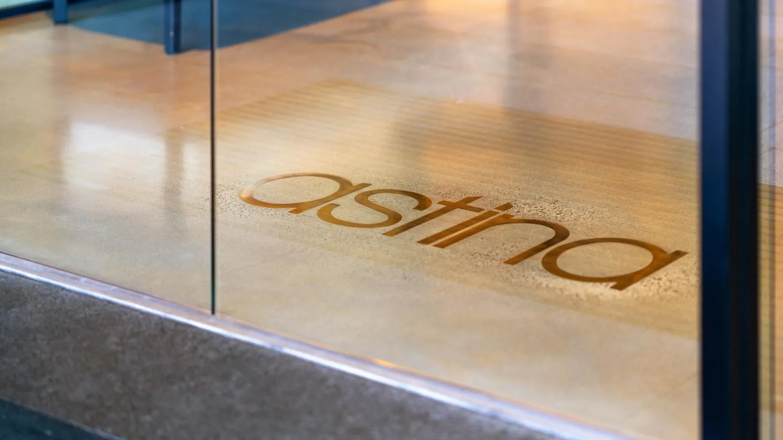 Brass Astina logo inlaid in the polished floor at the Astina Suites entrance