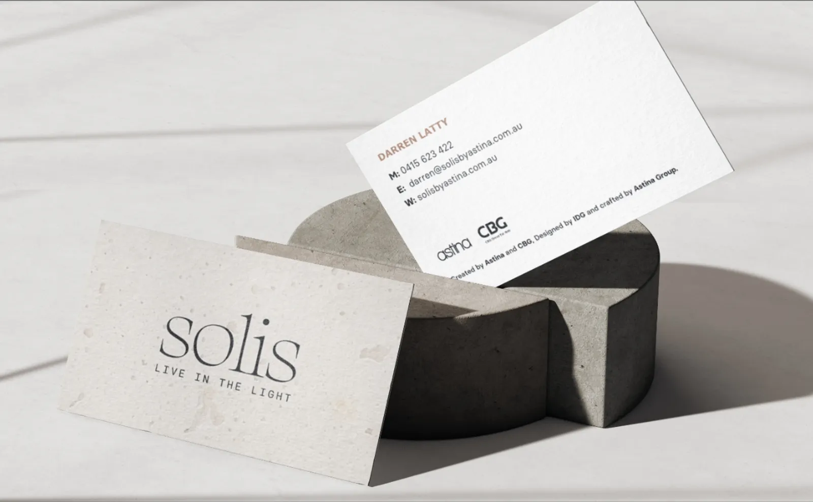 "Live in the light" business cards for Solis, leaning against a concrete block