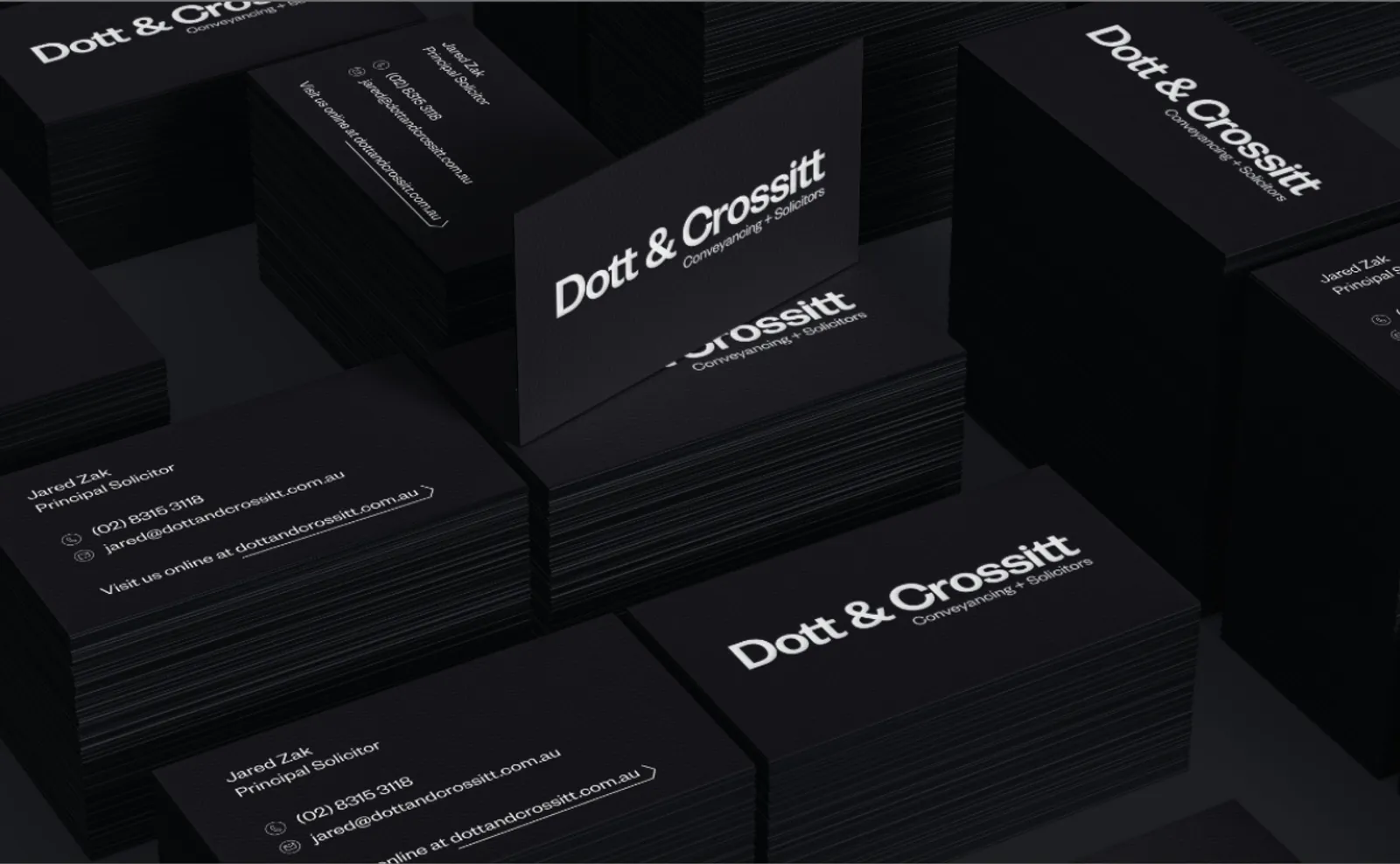 Stacks of black Dott & Crossitt business cards printed with the Conveyancing + Solicitors wordmark