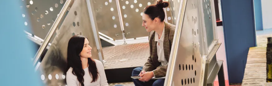 Two Q Agency team members talking on the office stairs